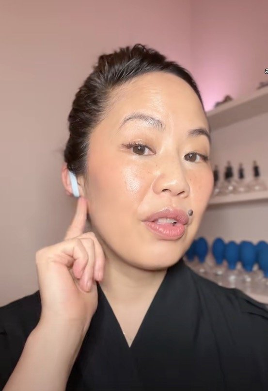 Beauty enthusiast on TikTok showcasing her face appearing firmer and more defined using a white rubber bands for an elastic ear