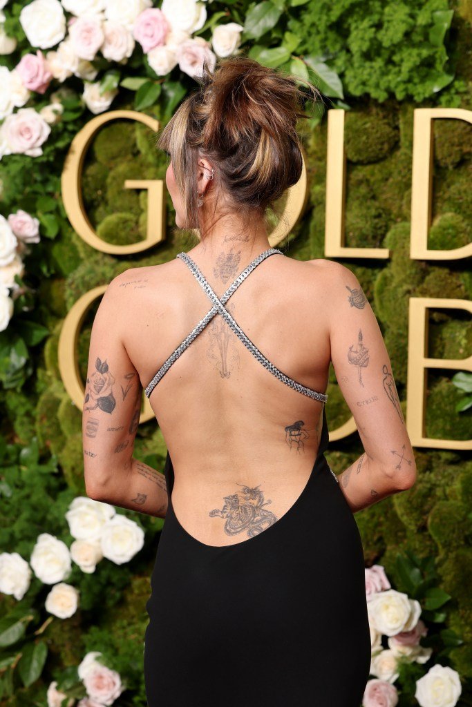 Miley Cyrus in a black dress showcasing her tattoo at the 82nd Annual Golden Globe Awards in Beverly Hills, California