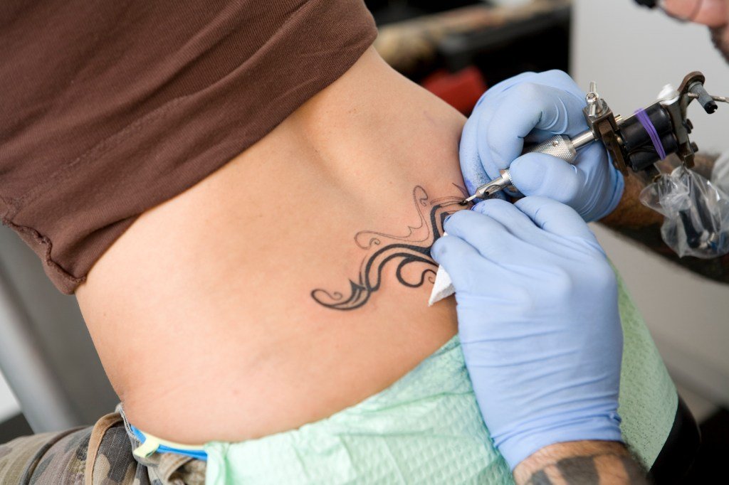 Tattoo artist working on a lower back tattoo
